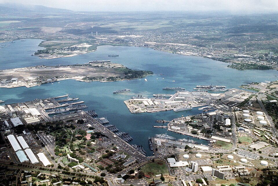 Aerial view of Pearl Harbor, Ford Island in center. The Arizona Memorial is the small white speck on the far right side close to Ford Island.