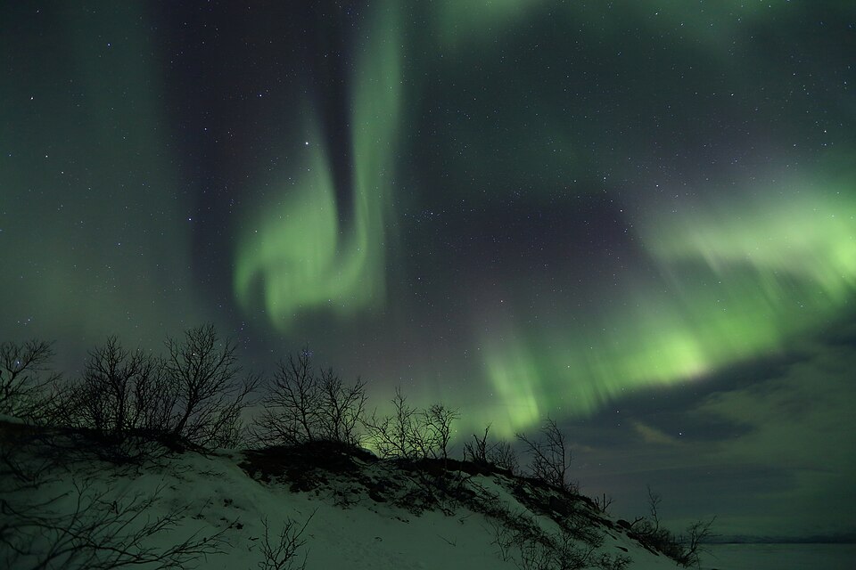 The solar wind moving through the magnetosphere changes how the charged particles in the Earth's thermosphere or exosphere move, and the resulting ionization of these particles causes them to emit light of different colors, thus forming auroras near the polar regions.