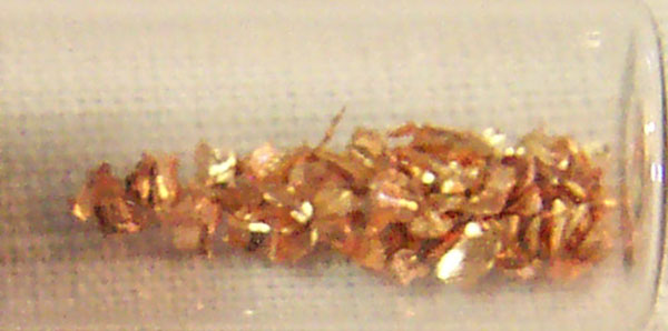 Some small pieces of copper in a tube. Recently processed copper is a pink color. The color changes to the more familiar orange when it reacts with air.