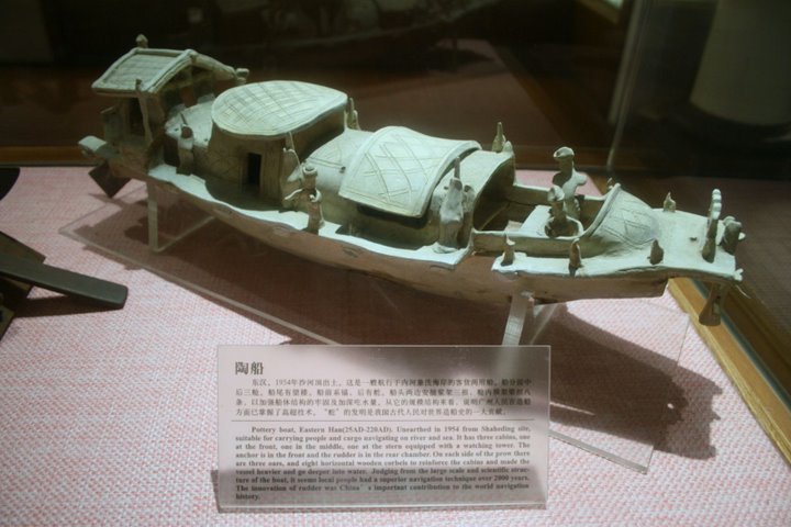 An Eastern Han (25–220 AD) Chinese pottery boat fit for riverine and maritime sea travel, with an anchor at the bow, a steering rudder at the stern, roofed compartments with windows and doors, and miniature sailors