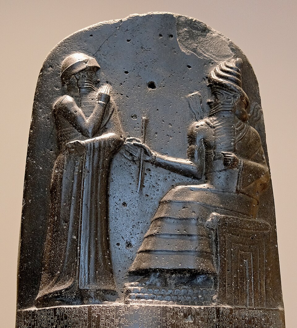 Hammurabi (standing), depicted as receiving his royal insignia from Shamash (or possibly Marduk). Hammurabi holds his hands over his mouth as a sign of prayer (relief on the upper part of the stele of Hammurabi's code of laws).