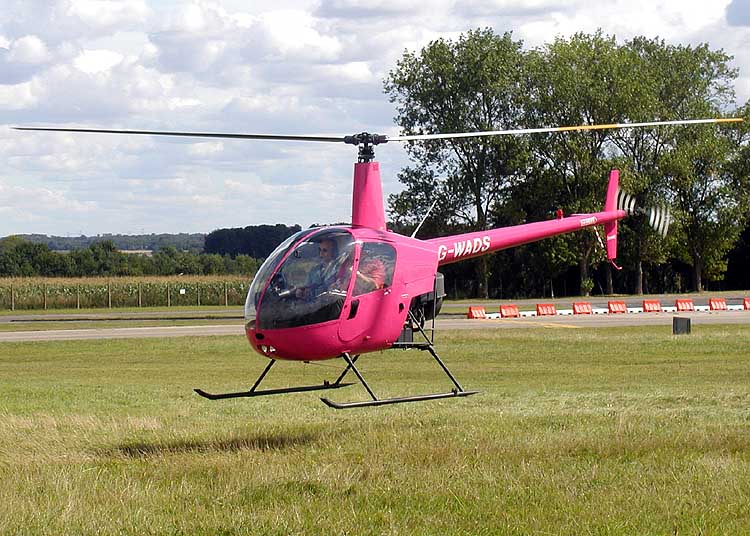 A Robinson R22 Alpha helicopter flying just a little above the ground