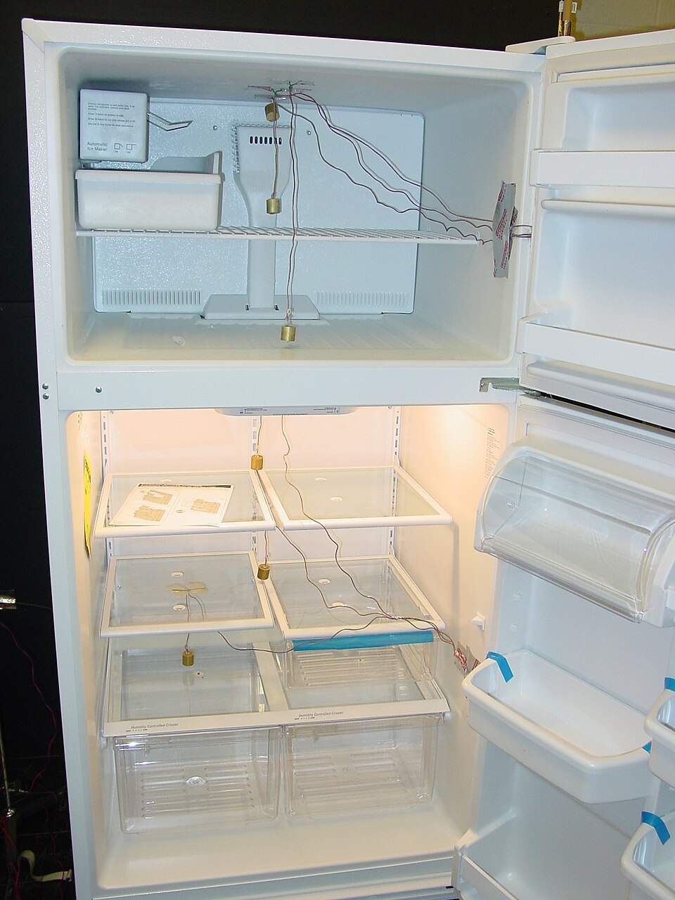 A domestic refrigerator with an opened freezer compartment at the top and an opened refrigerator compartment at the bottom