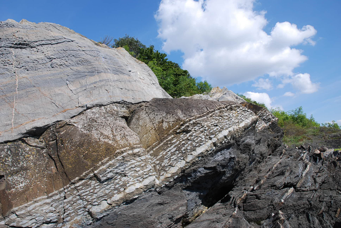 Photo of the Ordovician–Silurian boundary. Due to the folding of the Caledonian mountain range, the layers have been inverted (turned right over). This left the earlier Ordovician limestone sitting on top of the later Silurian brownish mudstone.