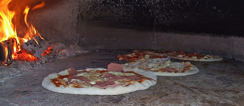 Pizzas bake in a traditional wood-fired brick oven
