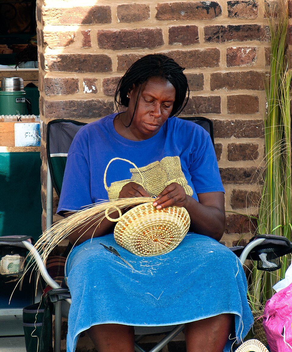 A gullah woman makes a sweetgrass basket in Charleston's City Market